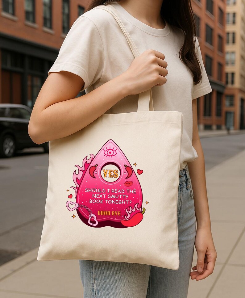 Op de afbeelding: Een witte tote bag met een roze en rode afbeelding van een Ouija-bord met de tekst "YES" en "SHOULD I READ THE NEXT SMUTTY BOOK TONIGHT? GOOD BYE".