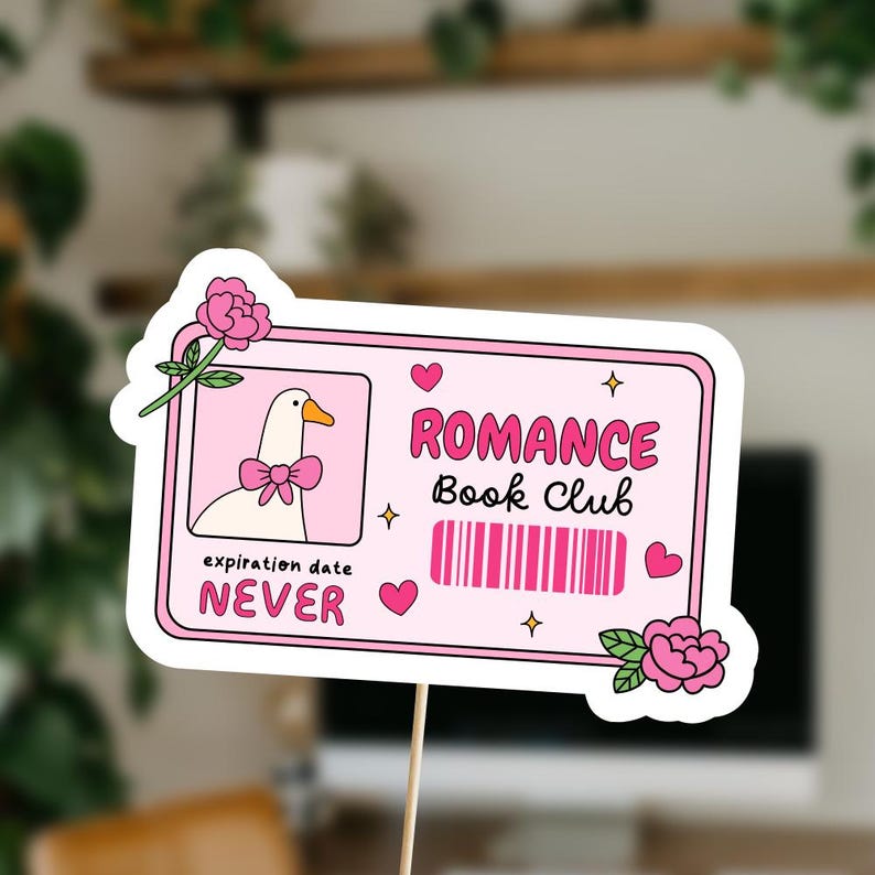Pu&ograve; includere: Un adesivo rosa e bianco con un'oca di cartone animato che indossa un fiocco rosa. L'adesivo dice "Romance Book Club" e "expiration date NEVER".