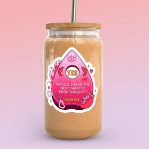 May include: A glass tumbler with a wooden lid and a metal straw. The tumbler has a sticker with a pink Ouija board design, flames, and the text "SHOULD I READ THE NEXT SMUTTY BOOK TONIGHT? GOOD BYE."