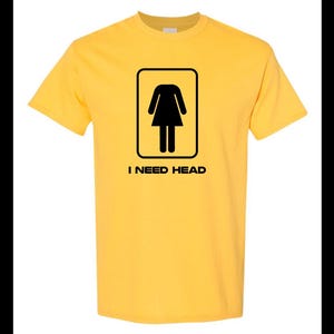 May include: Yellow t-shirt with a black silhouette of a woman in a dress inside a square and the text "I NEED HEAD" below.