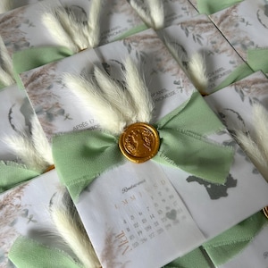 Faire-part format pochette avec ruban, fleurs séchées et cachet de cire : l’élégance au service de vos plus beaux moments.