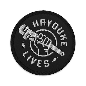 May include: Embroidered patch with the words "HAYOUKE LIVES" in white thread on a black circular background. A white wrench and a fist are in the center of the design. Two lightning bolts flank the text.