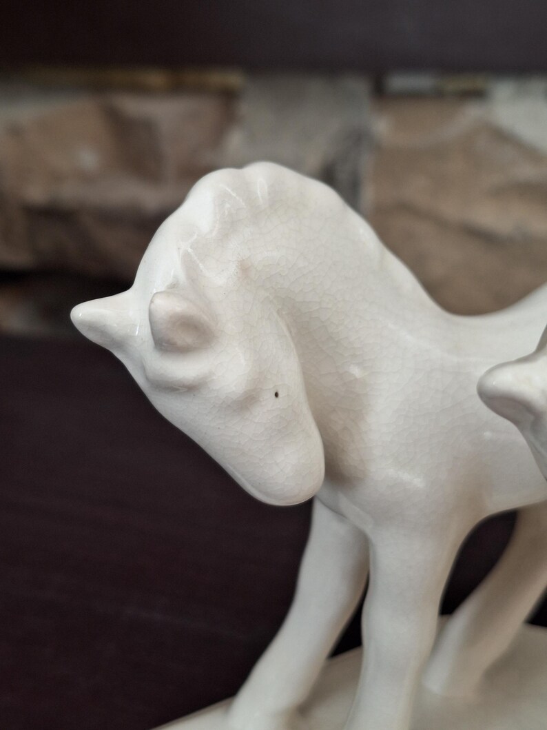 Pode incluir: Um close-up de uma estatueta de cavalo de cer&acirc;mica branca. O cavalo est&aacute; em p&eacute; com a cabe&ccedil;a ligeiramente virada. A cer&acirc;mica tem um acabamento craquelado e os detalhes das caracter&iacute;sticas do cavalo s&atilde;o vis&iacute;veis.