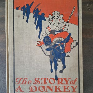 Może przedstawiać: Vintage okładka książki zatytułowana "The Story of a Donkey" autorstwa Mme. De Segur. Okładka przedstawia niebieską ilustrację osoby jadącej na osiołku, z czerwonym i pomarańczowym tłem. Sylwetki ludzi znajdują się w lewym górnym rogu.