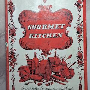May include: A red and white book cover with the title "Evelyn Tristram's Gourmet Kitchen" in black lettering. The cover features a decorative border with floral designs and a drawing of kitchen utensils, including a rolling pin, a whisk, and a bottle.