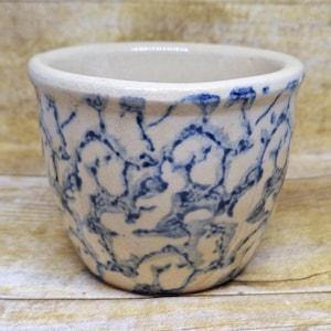 May include: A white ceramic mug with a black handle and the text "But First, Coffee" in a black, bold font. The mug is sitting on a white surface. The mug is approximately 4 inches tall.