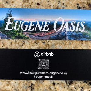 May include: Two rectangular cards. The top card features a scenic landscape with the text "EUGENE Oasis" in white. The bottom card is black with the Airbnb logo, a QR code, and Instagram and hashtag information.