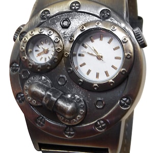 K&ouml;nnte beinhalten: Eine Armbanduhr im Steampunk-Stil mit silberner und goldener Oberfl&auml;che. Die Uhr hat zwei runde Zifferbl&auml;tter mit wei&szlig;en Zifferbl&auml;ttern und schwarzen Zeigern. Das Zifferblatt der Uhr ist von einem runden Metallrahmen mit einem dekorativen Design umgeben. Das Armband der Uhr ist aus braunem Leder.