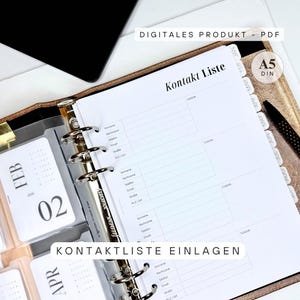 Könnte beinhalten: A5-Kontaktlisteneinlage für einen Ordner. Das weiße Papier hat ein Kontaktformular-Layout mit Feldern für Name, Telefon und E-Mail. Der Ordner ist geöffnet und zeigt monatliche Kalenderregisterkarten und den Text "DIGITALES PRODUKT - PDF".