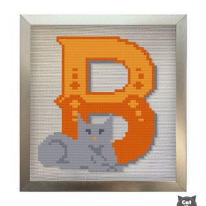 May include: A framed cross-stitch design featuring the letter "B" in orange with a gray cat sitting in front of it.