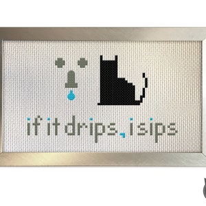 May include: A framed cross-stitch design with a black cat and a dripping faucet. The text reads "if it drips, I sips".