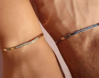 May include: Two gold bracelets with the inscription "always side by side" on one and "always side by side" on the other.