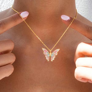 Pu&ograve; includere: Una collana con catena dorata con un ciondolo a forma di farfalla. La farfalla &egrave; realizzata in smalto bianco con accenti rosa, blu e verdi.
