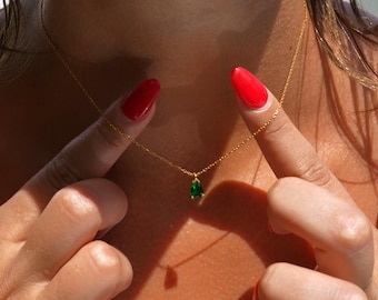 May include: A gold chain necklace with a teardrop-shaped green gemstone pendant.