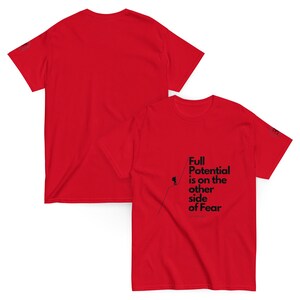 May include: Two red t-shirts. One shirt displays the text "Full Potential is on the other side of Fear" in black, along with a small graphic of a person climbing. The other shirt is plain red.