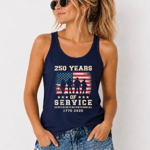May include: A navy blue tank top featuring a graphic print of the American flag with four soldier silhouettes. The text reads 250 YEARS OF SERVICE SEMIQUINCENTENNIAL 1776-2026 in a distressed white font, centred above and below the flag design.