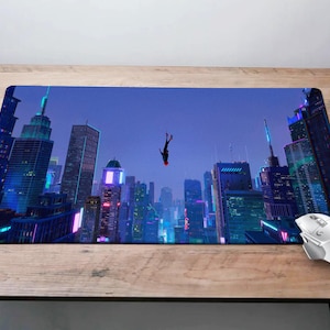 May include: A black and red figure falls against a backdrop of a city skyline at night. The city is illuminated with neon lights and the sky is a dark blue.