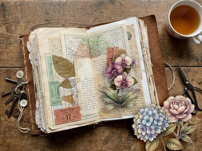 Op de afbeelding: Een open dagboek met een bruine leren kaft, versierd met vintage ephemera zoals een landkaart, toegangskaartjes en gedroogde bladeren. De pagina's zijn gedecoreerd met illustraties van paarse orchidee&euml;n, blauwe hortensia's en een roze pioenroos.