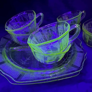 Può includere: Un set di quattro tazze da tè in vetro trasparente verde e un piattino abbinato. Le tazze e il piattino hanno un delicato design inciso.