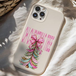 May include: A cream-colored smartphone case featuring a graphic of a stylized Christmas tree made of layered ribbons in shades of pink, teal, and white. The text "OH CHRISTMAS TREE" is printed in pink capital letters above the tree illustration.