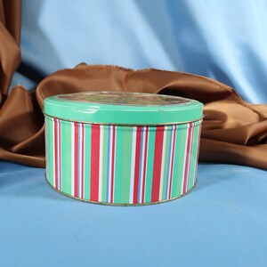 May include: A round, striped tin with a turquoise lid. The tin has red, green and white stripes.