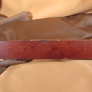 May include: A wooden level with a brass level indicator. The level is dark brown and has a slightly curved shape.