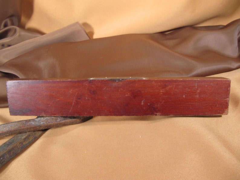 May include: A wooden level with a brass level indicator. The level is dark brown and has a slightly curved shape.