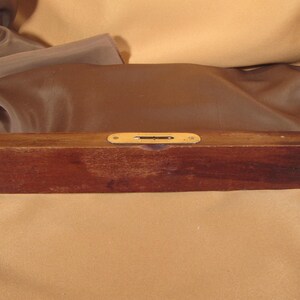 May include: A wooden level with a brass level indicator. The level is brown and has a natural wood finish.