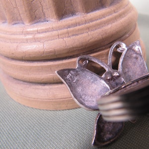 May include: Silver butterfly ring with a textured surface. The ring is in focus and the background is out of focus.