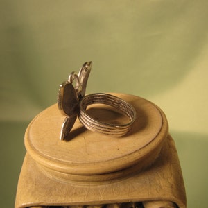 May include: Silver ring with a butterfly design. The ring is made of multiple bands and has a detailed butterfly design.