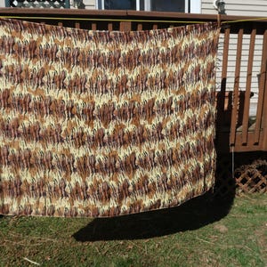May include: A rectangular fabric textile featuring a repeating tiger stripe pattern in shades of dark brown, black, and cream. The material is draped horizontally and displays a textured surface with vertical lines of color across the entire piece.