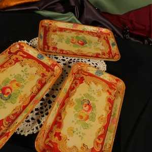 Könnte beinhalten: Drei dekorative Tabletts mit verzierten goldenen und roten bemalten Rändern und Blumendesigns. Die Tabletts sind aus Holz und haben einen Vintage-Look.
