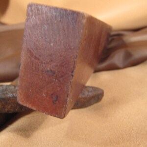 May include: Close-up of a wooden block with a dark brown colour. The block has a smooth surface and is slightly rounded on the edges. The block has the number "2" written on it.