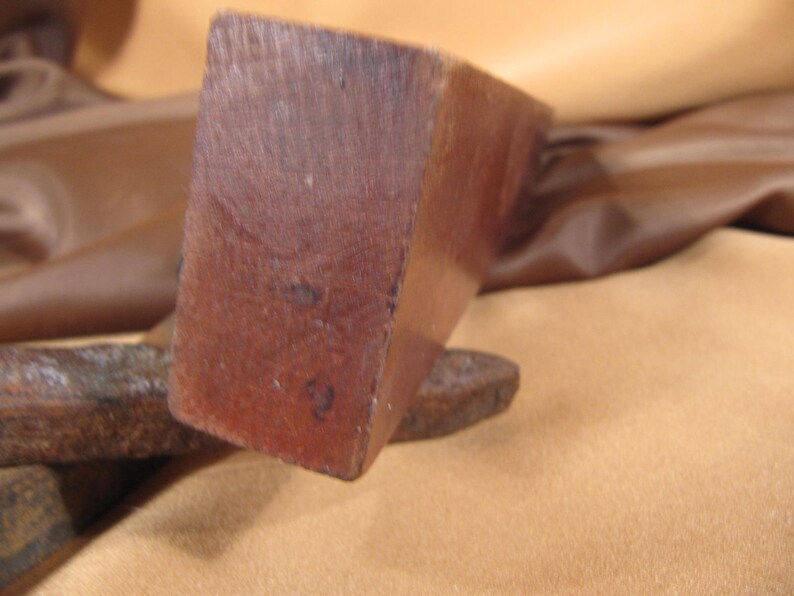 May include: Close-up of a wooden block with a dark brown colour. The block has a smooth surface and is slightly rounded on the edges. The block has the number "2" written on it.