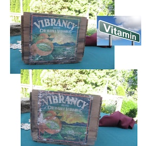 May include: Two vintage wooden boxes with a faded label that reads "Vibrancy Brand Chewable Vitamin C". The boxes are sitting on a blue tablecloth. A green street sign with the word "Vitamin" is in the background.