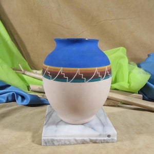 Może przedstawiać: Niebiesko-biały ceramiczny wazon z geometrycznym wzorem. Wazon stoi na białej marmurowej podstawie.