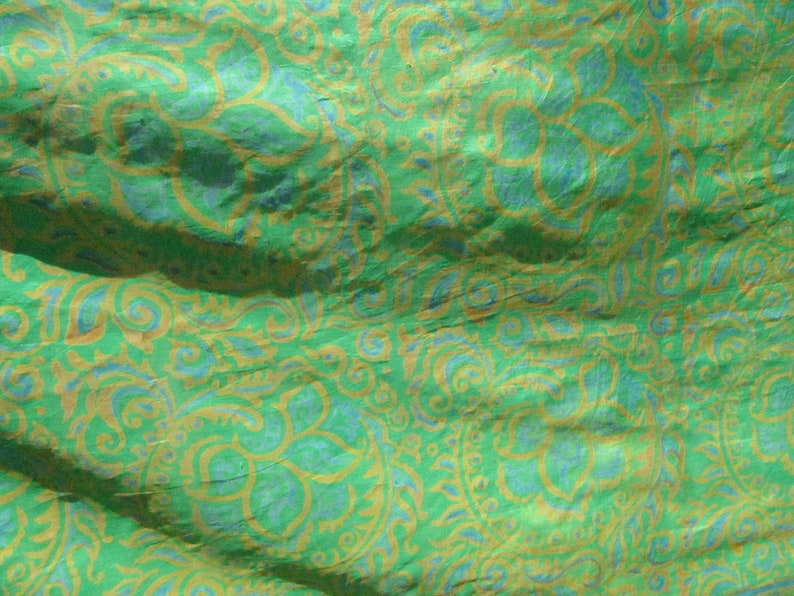 Może przedstawiać: Zielony materiał z niebieskim i złotym wzorem paisley. Materiał ma pomarszczoną fakturę.
