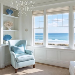 Könnte beinhalten: Ein helles, luftiges Zimmer mit Küstendekoration. Es verfügt über einen hellblauen Sessel mit passendem Kissen, eingebaute weiße Regale mit Muschel- und Korallenakzenten und große Fenster mit Blick auf das Meer. Der Raum ist in Weiß- und Blautönen gehalten.