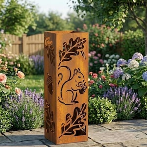 May include: A rectangular, rusty-brown metal garden sculpture. The sculpture features cut-out designs of a squirrel holding an acorn, oak leaves, and acorns. The sculpture is placed on a stone patio in a garden with flowers and greenery.