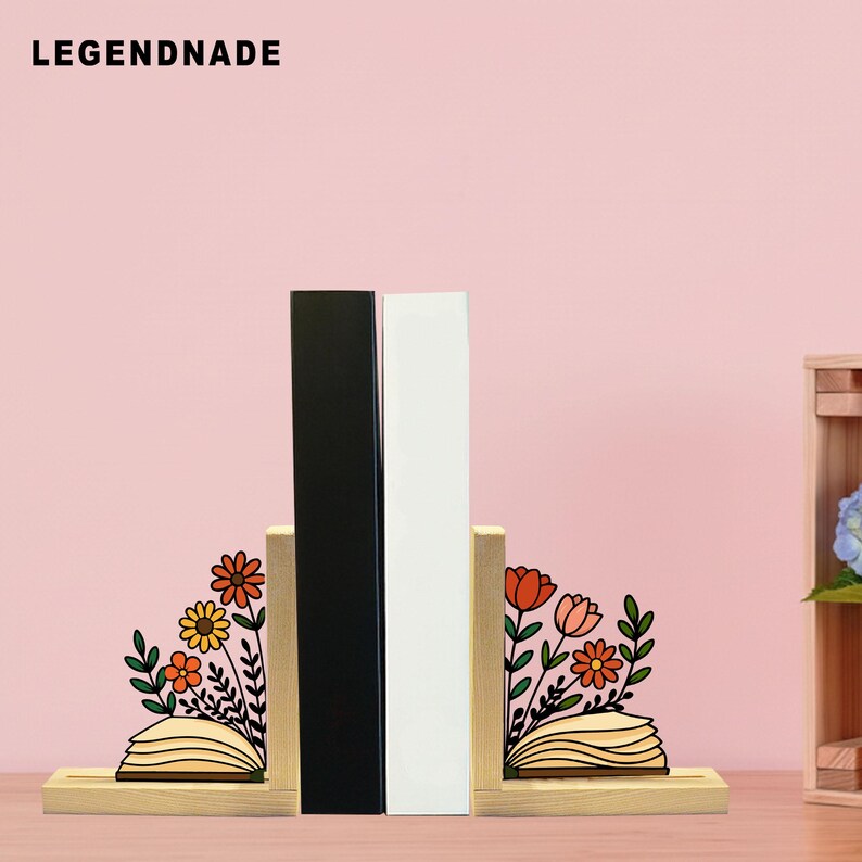 May include: Wooden bookends with floral designs and the text "LEGENDNADE" at the top. The bookends feature a black and a white book between them. The floral designs include orange, yellow, and red flowers with green leaves.