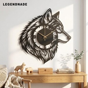 Könnte beinhalten: Eine schwarze Wanduhr in Form eines Wolfskopfes mit einem runden Zifferblatt, goldenen Zeigern und schwarzen Ziffern. Der Text LEGENDNADE steht in der oberen linken Ecke. Das Design zeigt filigrane Ausschnitte für Fell und Gesichtszüge.