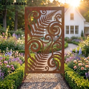 May include: A rectangular metal garden screen with a rust-colored finish featuring a laser-cut design of two large fern fronds surrounded by swirling scrollwork patterns. The panel is positioned vertically on a gravel path.
