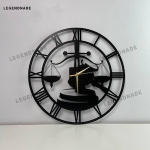 Op de afbeelding: Zwarte metalen wandklok met Romeinse cijfers en een juridisch thema. Het ontwerp van de klok omvat een hamer, weegschaal van de rechtvaardigheid en een cirkelvormig frame. De wijzers zijn goudkleurig. De merknaam "LEGENDNADE" staat linksboven.