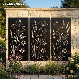 Könnte beinhalten: Drei rechteckige schwarze Metallpaneele mit lasergeschnittenen Blumen- und Pflanzenmotiven. Jedes Paneel zeigt eine einzigartige Anordnung von Wildblumen, Gänseblümchen und hohen Gräsern. Der Text LEGENDNADE ist oben links zu sehen.