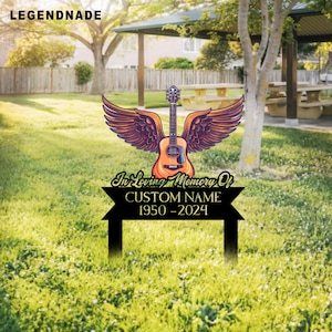 Könnte beinhalten: Ein schwarzer Metall-Gartenstecker mit Gitarren- und Engelsflügel-Design. Die Gitarre ist braun und orange, mit dunkelvioletten Flügeln. Der Stecker enthält den Text "In Loving Memory Of", "CUSTOM NAME" und die Jahre "1950-2024".