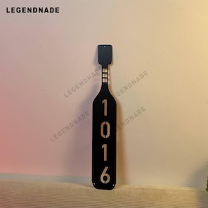 Peut inclure: Plaque de numéro de maison en forme de bouteille de vin en métal noir avec les chiffres 1016 en or.