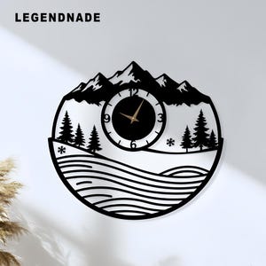 Può includere: Orologio da parete nero con un design di montagna e foresta. Il quadrante dell'orologio è nero con lancette dorate e numeri bianchi. L'orologio è rotondo e presenta il testo "LEGENDNADE" in alto.