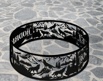 Könnte beinhalten: Ein schwarzer Feuerstellenring aus Metall mit einem Berg- und Wolf-Silhouette-Design. Der Ring trägt die Aufschrift "ROAR" und "LEGENDNADE". Das Design umfasst Bäume, Berge und heulende Wölfe.