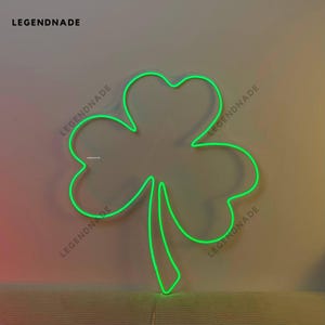 May include: A green neon light shaped like a four-leaf clover. The light is on a white wall.