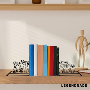 May include: Black metal dog-themed bookends with a rectangular base, holding a row of colorful books. The bookends feature dog silhouettes and the word "Name". The books are various colors, including blue, white, and red.